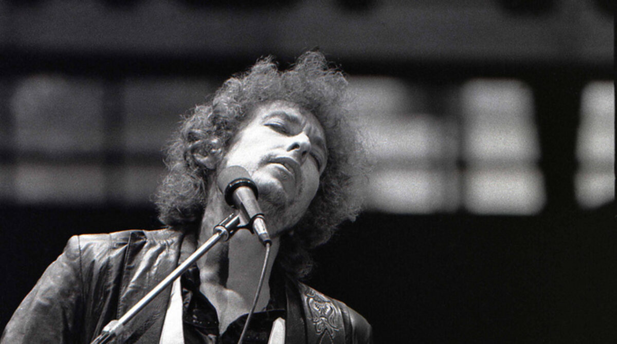 Bob Dylan performs in Rotterdam, June 23 1978, eyes closed at the microphone with a Fender Stratocaster, a folk rock in the 70s songwriter whose own singles never made this site's own chart archive