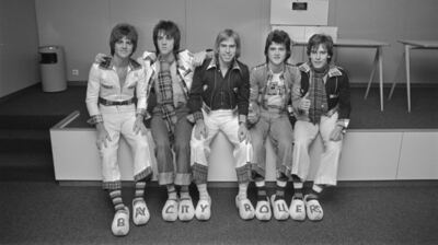 Bay City Rollers pose in matching tartan at Schiphol Airport in February 1976, wearing wooden clogs spelling out their name, one of the biggest pop songs of 70s teen-idol acts