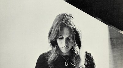 Carole King seated at a piano in a black and white Ode Records publicity photo from 1971