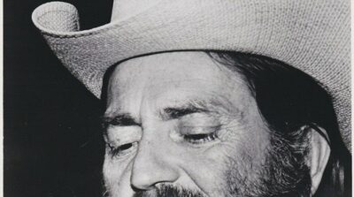Willie Nelson in a black and white Atlantic Records publicity photo from the early 1970s, wearing a straw cowboy hat and singing into a microphone